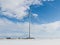 Windmill in the snowy valley under the bright cloudy sky