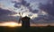 Windmill at sunrise in Netherlands. Beautiful old dutch windmill, green grass, fence against colorful sky with clouds