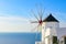 Windmill and traditional white buildings facing Aegean Sea in Oia, Santorini, Greece