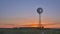 Windmill with a water pump against sunrise