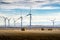 Windmills on agriculture fields producing alternative energy with round hay bales