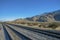 Windmills along a railroad track with mountains and clear blue sky views