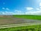 Windmills on the background of a green field and a blue cloudy sky. Wind turbine for power generation