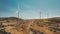 Windmills in brown desert. Wind power. Generator blades rotate. Alternative energy. Wind farms.
