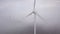 Windmills in the fog at sunrise. Wind turbine from aerial view. Sustainable development