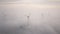 Windmills in the fog at sunrise. Wind turbine from aerial view. Sustainable development, environment friendly.