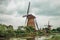 Windmills and garden on the bank of a large canal in a cloudy day at Kinderdijk.