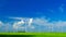 Windmills on a green field, on a bright sunny and windy day with forming cumulonimbus