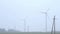 Windmills near the road foggy morning.