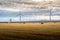 Windmills producing sustainable energy on the Alberta Prairies with round hay bales