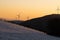 Windmills silhouette on a top of a mountain from afar with orange sunset sky