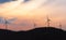 Windmills silhouette and a wooded hill at sunrise