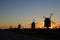 Windmills silhouettes by roadside at sunset