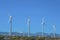 Windmills with three sharp blades against mountains and blue sky background