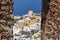 The windmills and white buildings of Oia, Santorini framed by a stone window in Oia castle