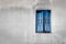 Window with closed blue shutters against a gray wall