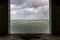 Window frame in derelict building looking out to stormy sea