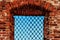 Window with iron grating in wall of ancient red brick building