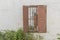 Window in an old, abandoned house, with wooden shutters and a rusty grill.