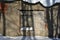 The window of the old brick building in cracked plaster covered with iron rusty grate, shadows of trees on the wall