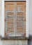 Window of old building covered by wooden blinds with peeling paint