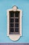 Window of an old building, palace. The frame is made of stucco in the Baroque style. White linen on a blue background of the walls