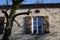 Window with open wooden shutters under the roof of an old stone house