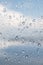 Window with rain waterdrops against blue sky