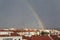 Window with raindrops with rainbow over buildings on the background