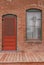 Window and red door on brick building with palm tree reflected in window