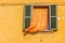 window with shutters and orange curtain