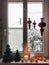 Window sill decorated of burning candles, fresh mandarines, paper Christmas toys and garland.