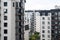 Window view of modern white apartment buildings with black roofs on a cloudy day. Cozy residential complex