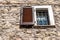 Window with the wooden shutter and the iron grate on old stone wall