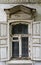 A window with wooden shutters and carved frames of the old house, with stucco elements on the facade