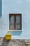 Window and a yellow postbox on a blue wall on a house