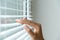 Windows jalousie. woman peeking through window blinds. Male hand separating slats of venetian blinds with a finger to