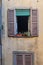 Windows with shutters on facade of residential building with flowers on it. Bergamo. Italy