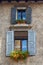 Windows with shutters on facade of residential building with flowers on it. Bergamo. Italy