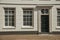 Windows and wooden door of gray elegant building facade on sunny day in Weesp.