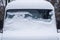 The windshield of the frozen minibus is covered with ice and snow on a winter day.