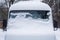 The windshield of the frozen minibus is covered with ice and snow on a winter day. Close up