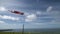 Windsock flying coastal breeze paraglider\'s soar overhead under a cumulus cloud