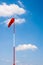 Windsock on pole against blue sky and clouds