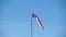 Windsock with red and white stripes show direction of wind blowing and speed. Cone wind indicator develops on blue sky background