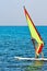 Windsurfer, blue sea and yellow sail. Surfer exercising in calm sea or ocean