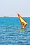 Windsurfer, blue sea and yellow sail. Surfer exercising in calm sea or ocean