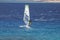 Windsurfer on a board under a sail against the background of the sea, wind and waves.