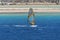 The windsurfer on the board under sail moves at a speed along the surface of the sea,