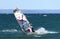 A windsurfer goes through a bend at high speed, riding in the waves with a autumn windy day